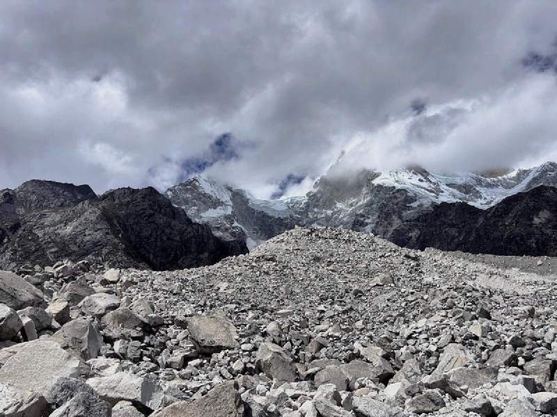 冰磧與雲:一整片碎石堆,後面的雪峰只露出一半。